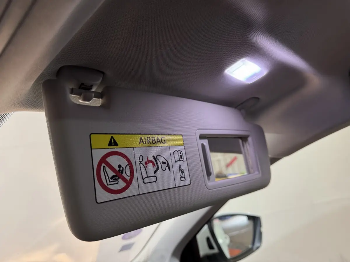 Détail du pare-soleil côté conducteur avec miroir éclairé dans l'habitacle clair d'un Skoda Karoq blanc.