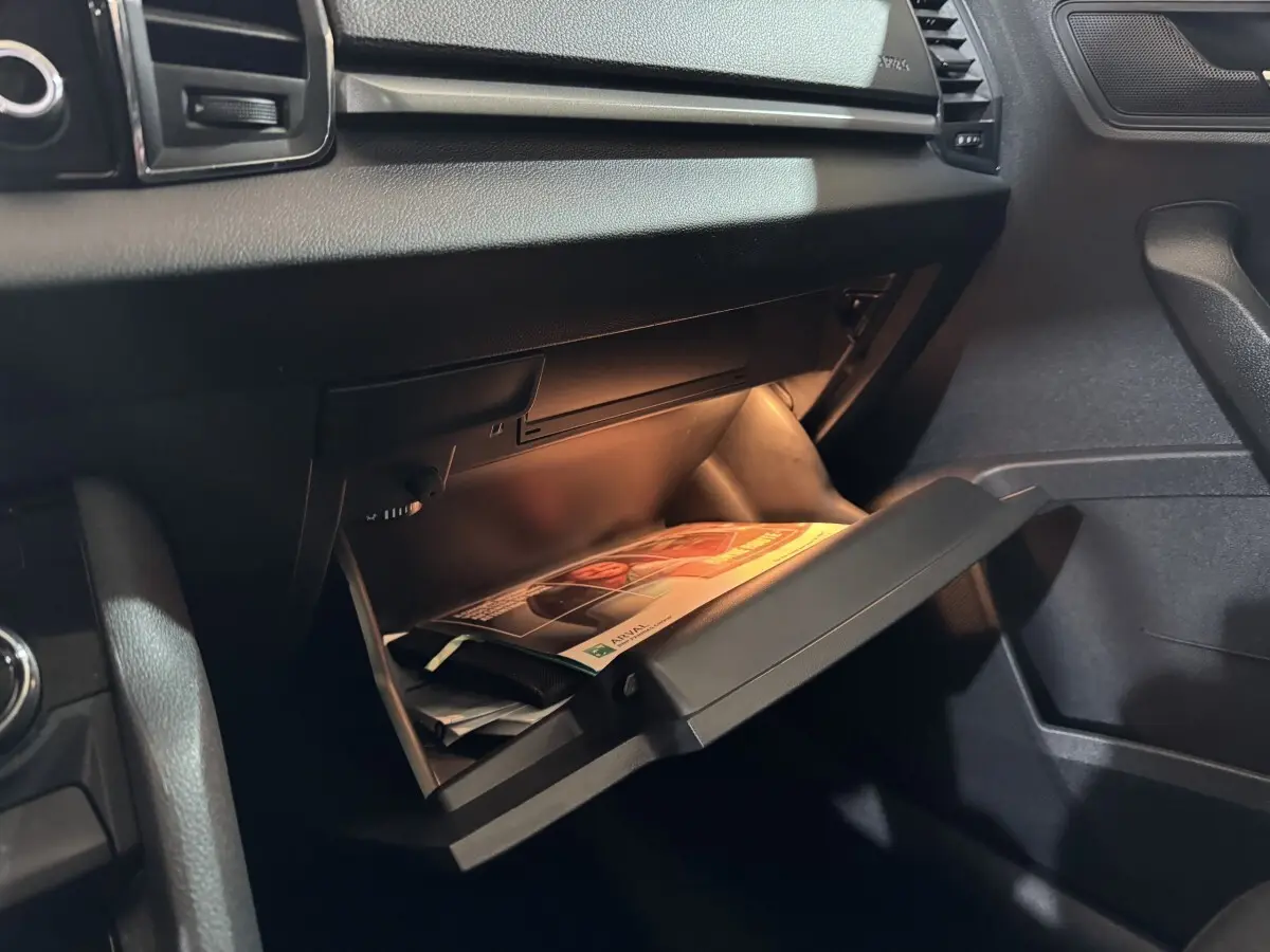 Gros plan sur la boîte à gants ouverte côté passager du Skoda Karoq 1.5 TSI blanc, intérieur noir.