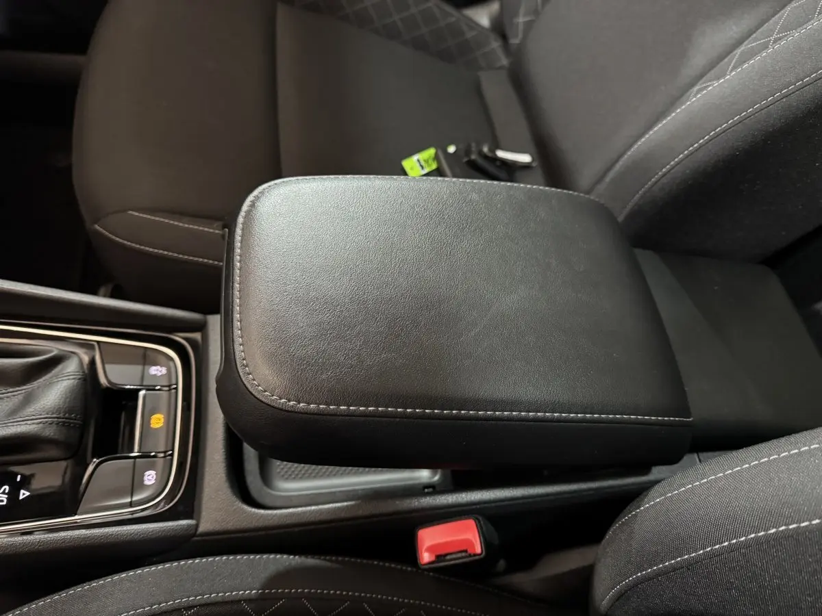 Accoudoir central noir en cuir avec coutures grises, entouré des sièges avant du Skoda Karoq 1.5 TSI 2021.