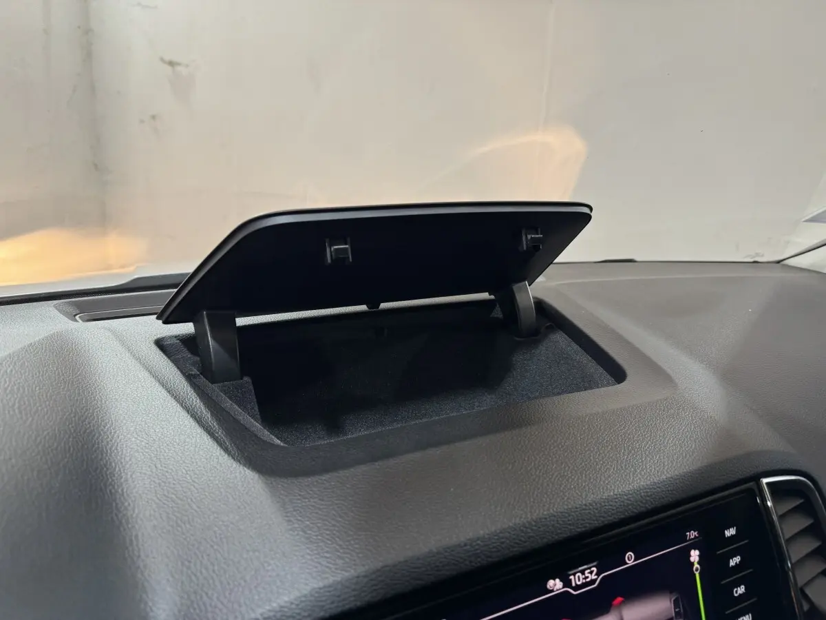 Rangement ouvert sur le tableau de bord noir d'un Skoda Karoq blanc, avec écran tactile visible en bas à droite.