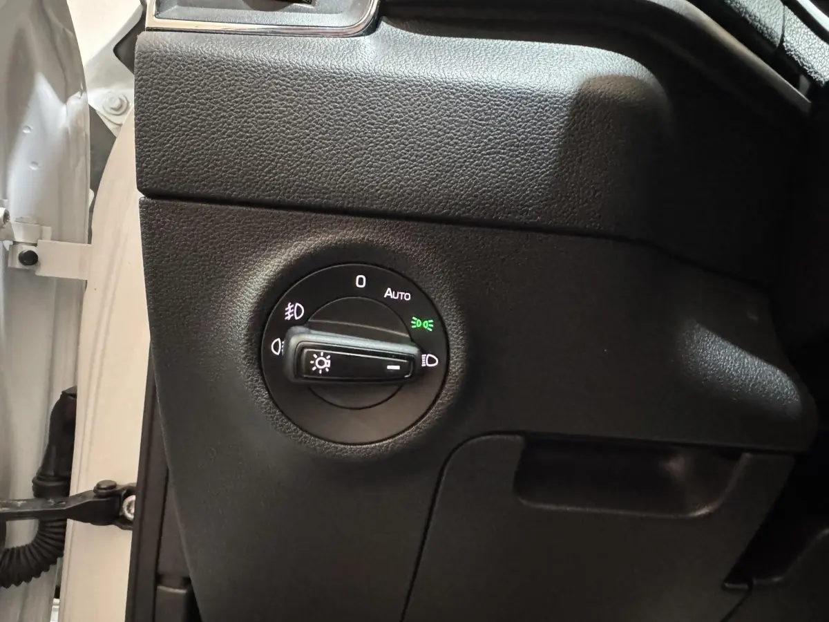 Gros plan sur le bouton de commande des phares du côté gauche d’un Skoda Karoq blanc 2021.