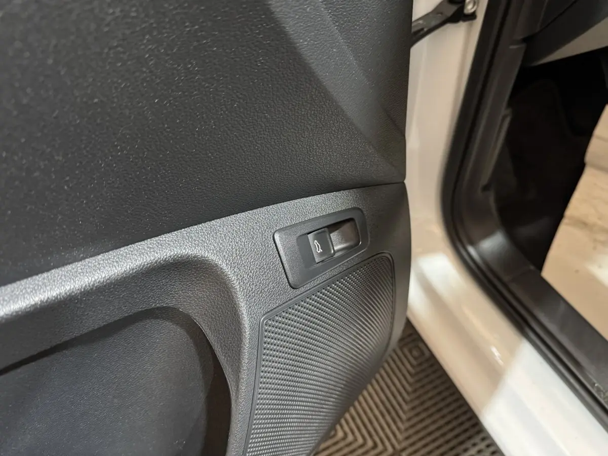 Détail du bouton d'ouverture électrique du coffre sur la porte côté conducteur d'un Skoda Karoq blanc 2021.