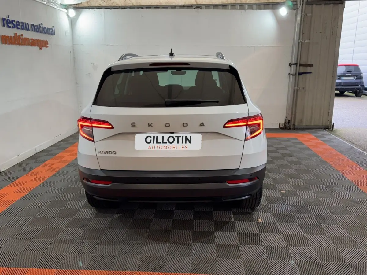 Vue arrière d'un Skoda Karoq blanc 2021 avec feux LED allumés dans un garage éclairé.