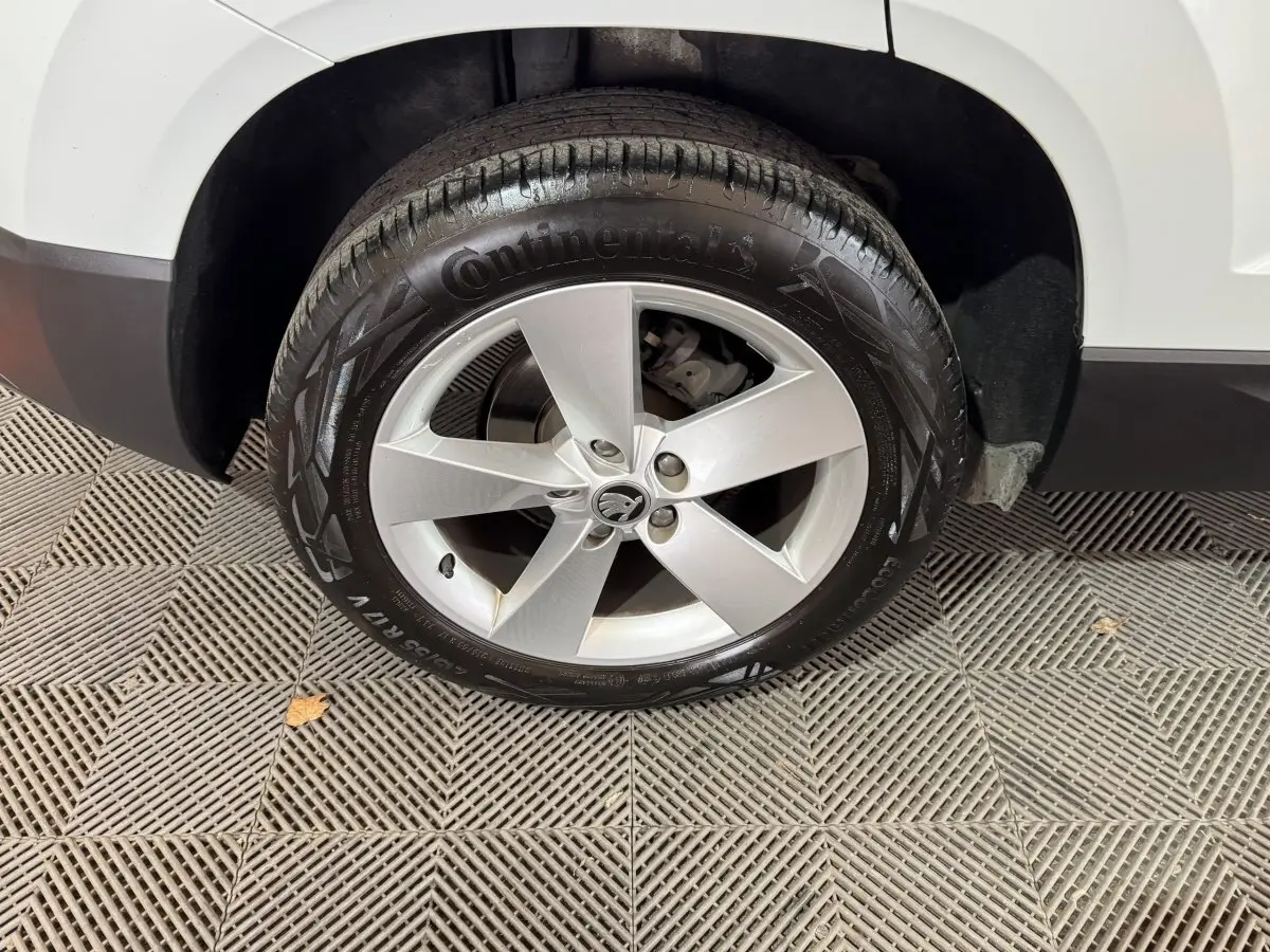 Gros plan sur la roue avant gauche blanche d’un Skoda Karoq 2021 avec jante argentée cinq branches.