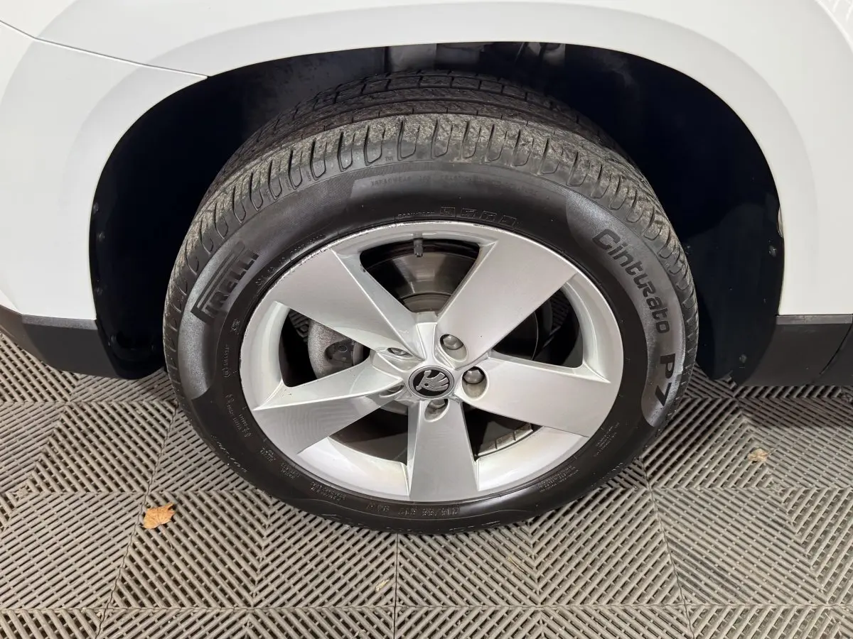 Gros plan sur la roue avant droite blanche d’un Skoda Karoq avec jante argentée à cinq branches.