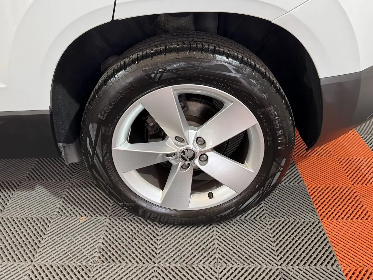 Gros plan sur la roue avant droite d'un Skoda Karoq blanc, avec jante alliage cinq branches et pneu Continental.
