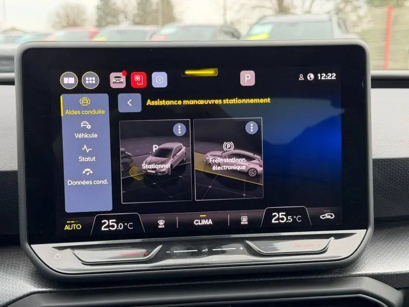 Écran tactile intérieur du SEAT LEON 2025 affichant l'assistance aux manœuvres de stationnement et la climatisation.