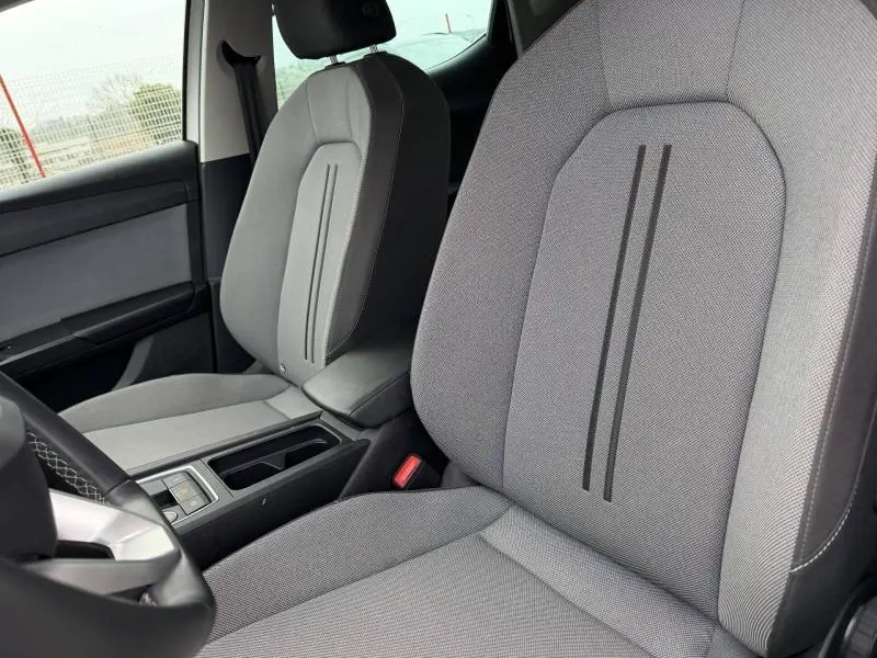 Vue intérieure rapprochée des sièges avant gris clair avec bandes noires du SEAT LEON 2025 côté conducteur.