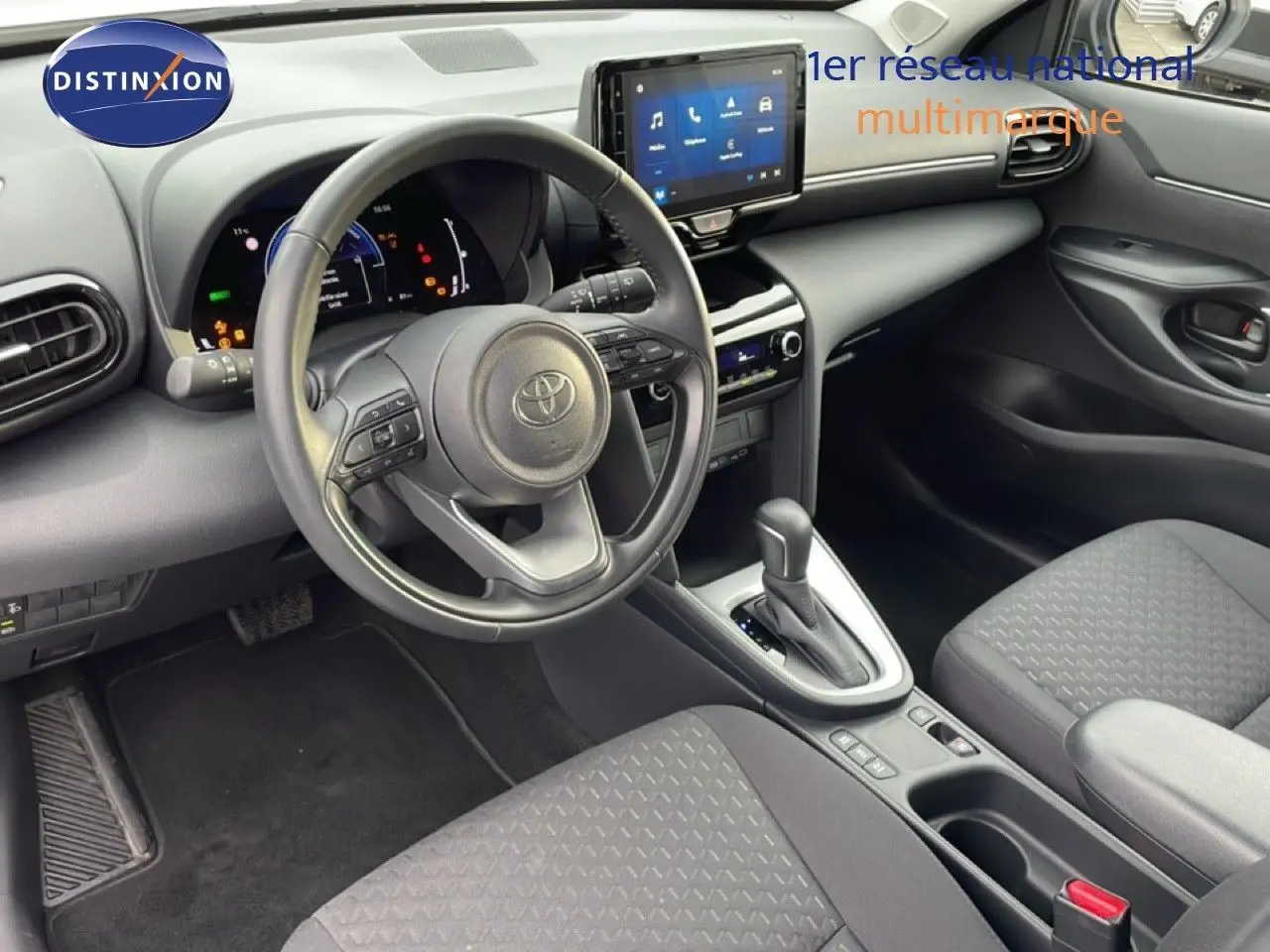 Vue intérieure côté conducteur de la Toyota Yaris Cross 2024, tableau de bord moderne avec écran tactile et volant multifonction noir.