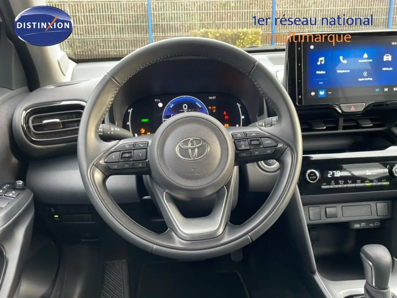 Vue intérieure centrée sur le volant et le tableau de bord du Toyota Yaris Cross blanc pur, avec écran tactile et commandes intégrées.