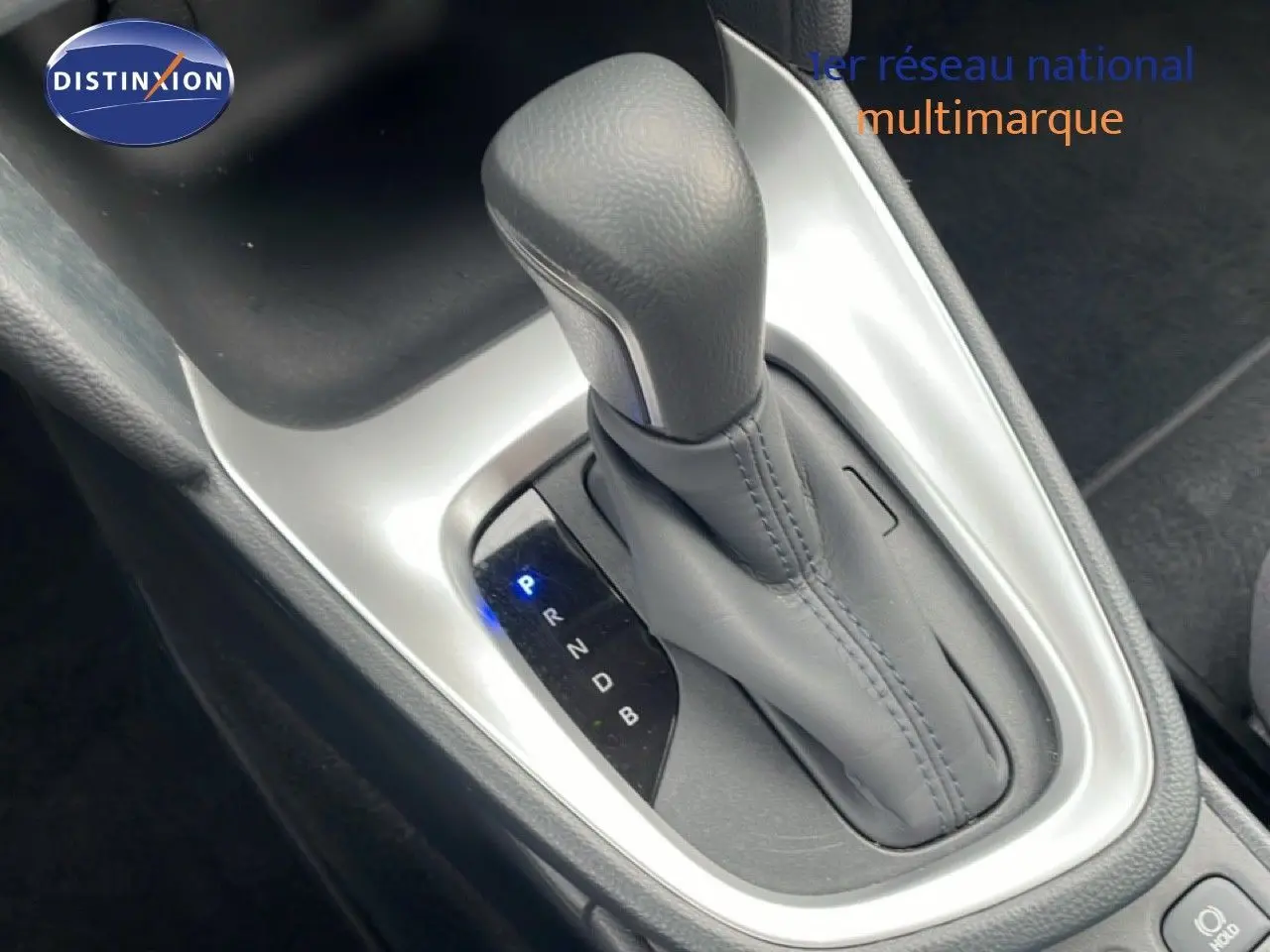 Gros plan sur le levier de vitesse automatique gris de la Toyota Yaris Cross 1.5 Hybrid 2024, entouré de plastique noir et argenté.