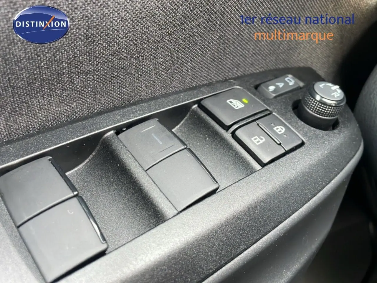 Gros plan sur les commandes de lève-vitres et réglage des rétroviseurs côté gauche d'une Toyota Yaris Cross blanche.