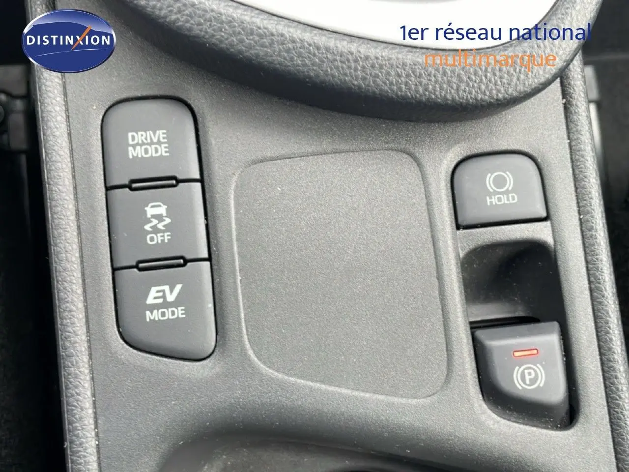 Gros plan sur la console centrale de la Toyota Yaris Cross blanche, montrant les boutons Drive Mode, EV Mode et frein à main électronique.