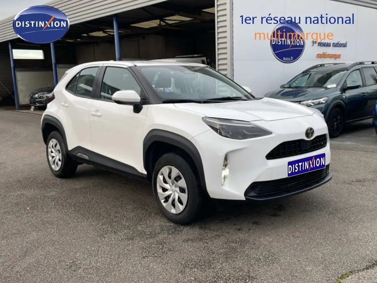 Toyota Yaris Cross blanc pur vue 3/4 avant droit, avec protections noires autour des roues et calandre noire.