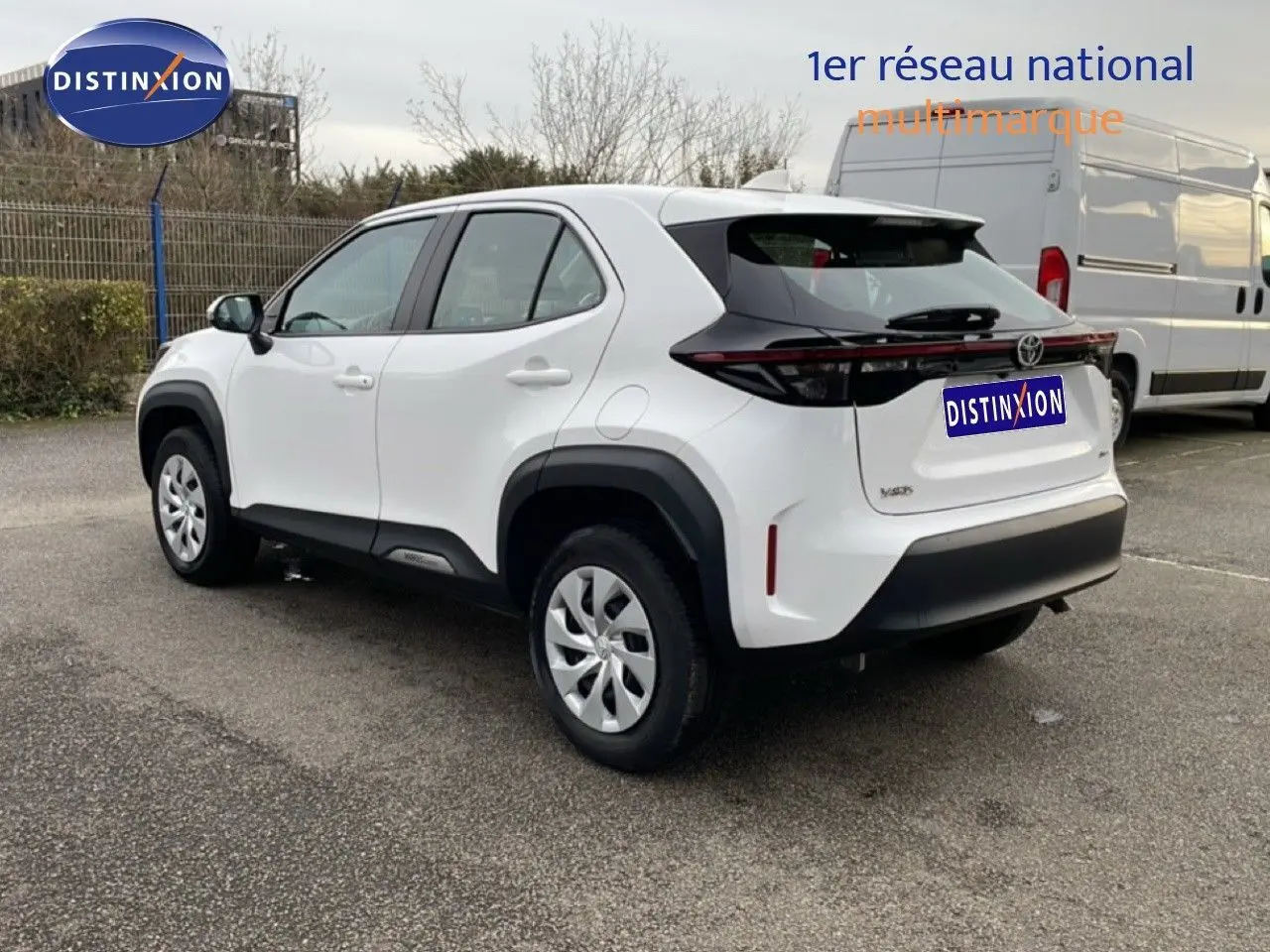 Toyota Yaris Cross blanc pur vue 3/4 arrière droit, avec protections noires contrastantes et jantes acier.