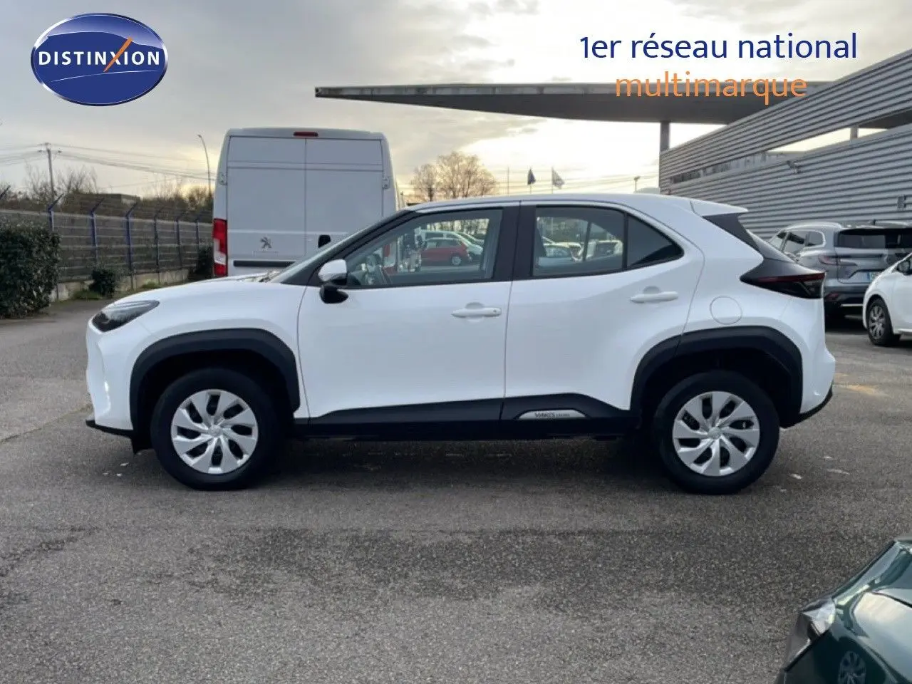 Vue latérale droite d'une Toyota Yaris Cross blanche pure 2024 avec protections noires et jantes acier.