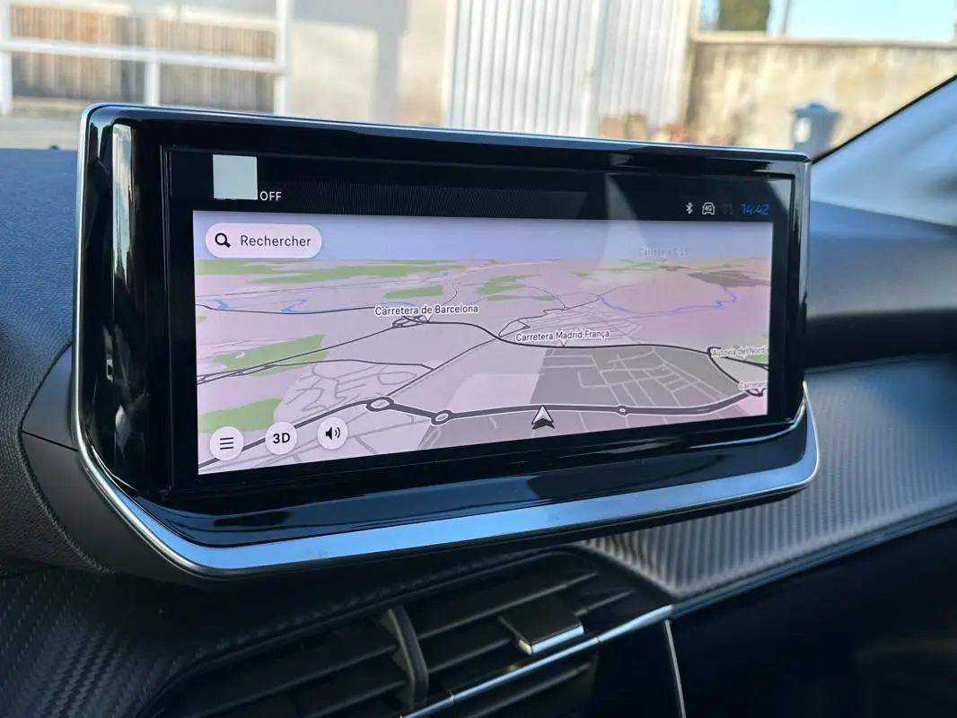 Écran tactile central affichant une carte de navigation dans l'habitacle d'une Peugeot 208 blanche, vue de profil intérieur.