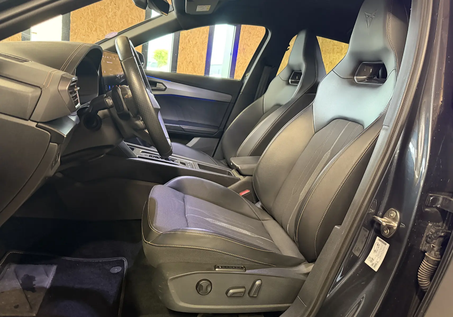 Vue intérieure côté conducteur de la CUPRA Formentor 1.4 Hybrid 245 DSG6 2023 avec sièges sport noirs et volant super sport.