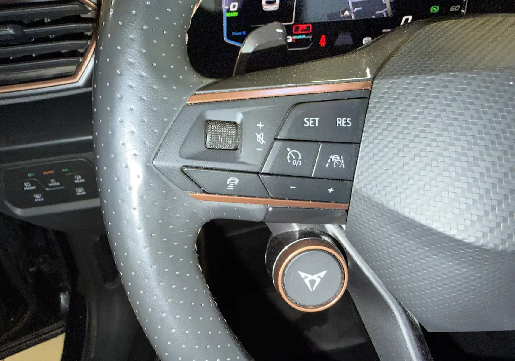 Gros plan sur le volant super sport noir perforé du CUPRA Formentor 1.4 Hybrid 245 avec commandes intégrées et détails cuivrés.