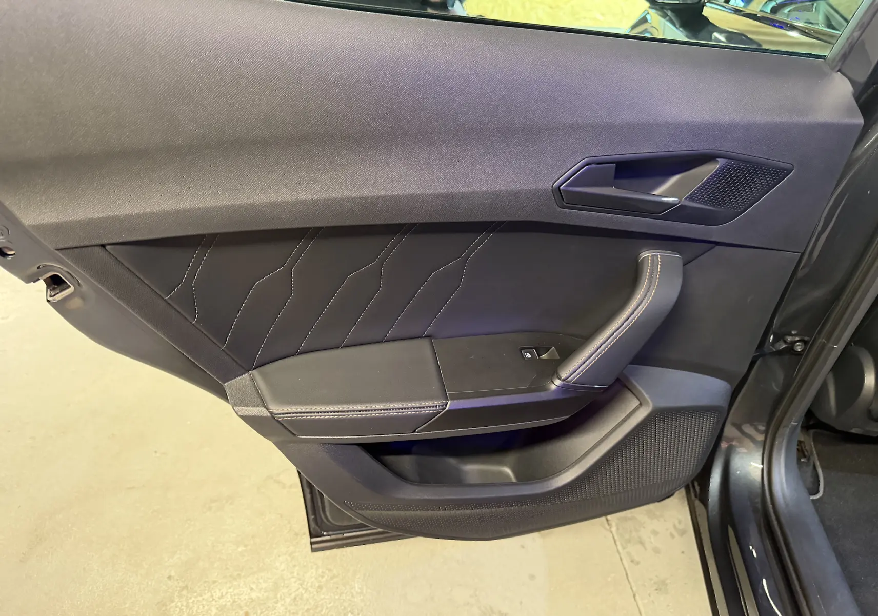 Vue rapprochée de la porte avant gauche noire du CUPRA Formentor 2023 avec surpiqûres apparentes et poignée intégrée.