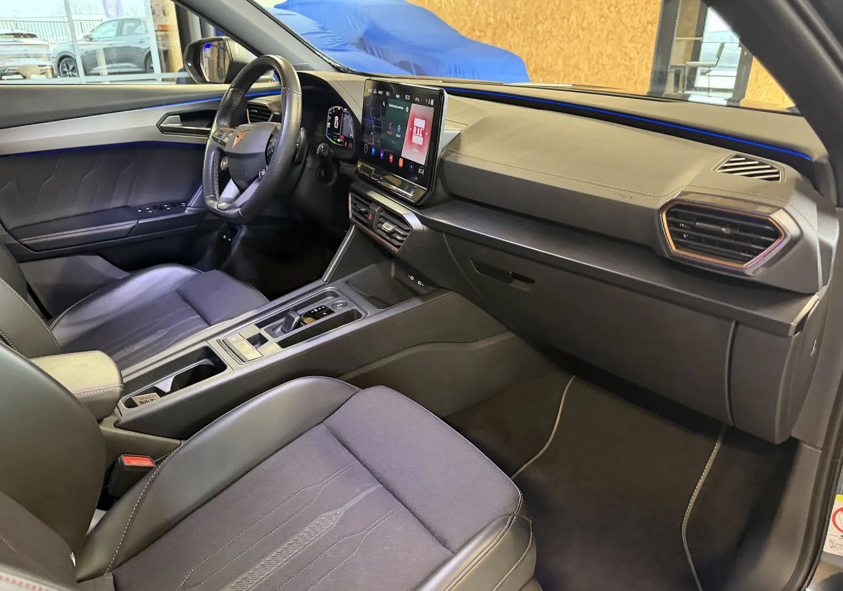 Vue intérieure côté conducteur de la CUPRA Formentor 1.4 Hybrid 2023, avec volant super sport et écran tactile central.