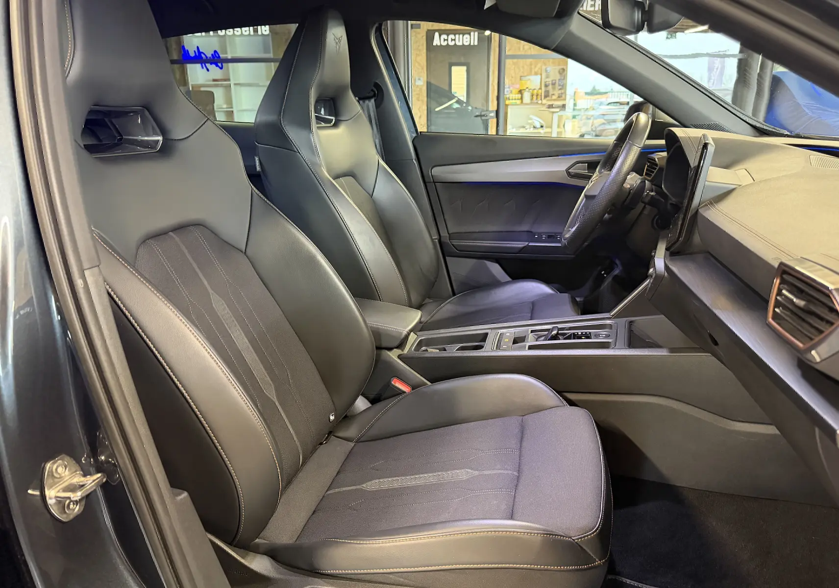 Vue intérieure côté gauche de la CUPRA Formentor 1.4 Hybrid 2023, sièges sport noirs avec surpiqûres cuivrées et volant super sport.