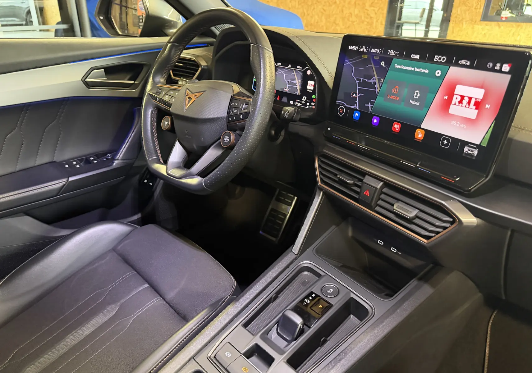 Vue intérieure côté conducteur de la CUPRA Formentor 1.4 hybride, volant super sport et écran tactile avec navigation affichés.