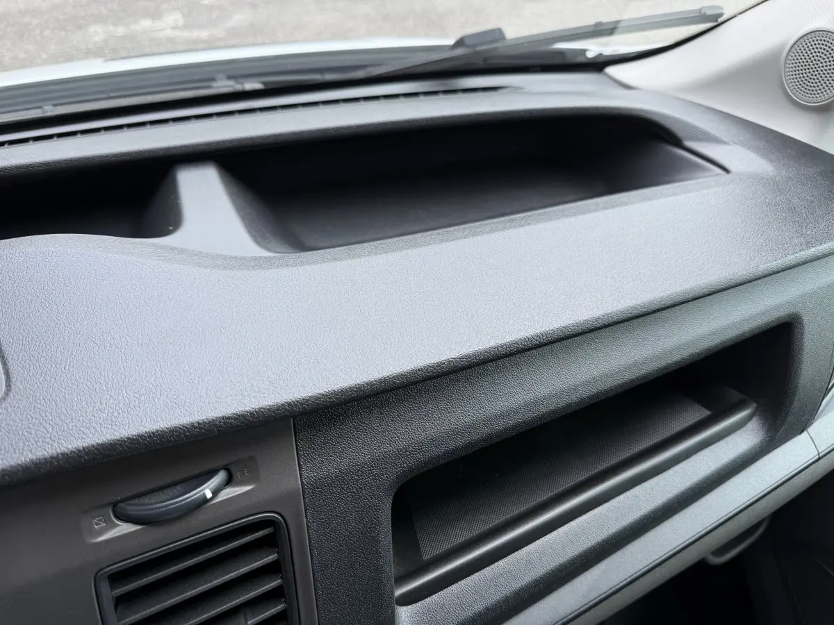 Détail de la planche de bord noire du Ford Transit Fourgon blanc, vue intérieure côté passager.