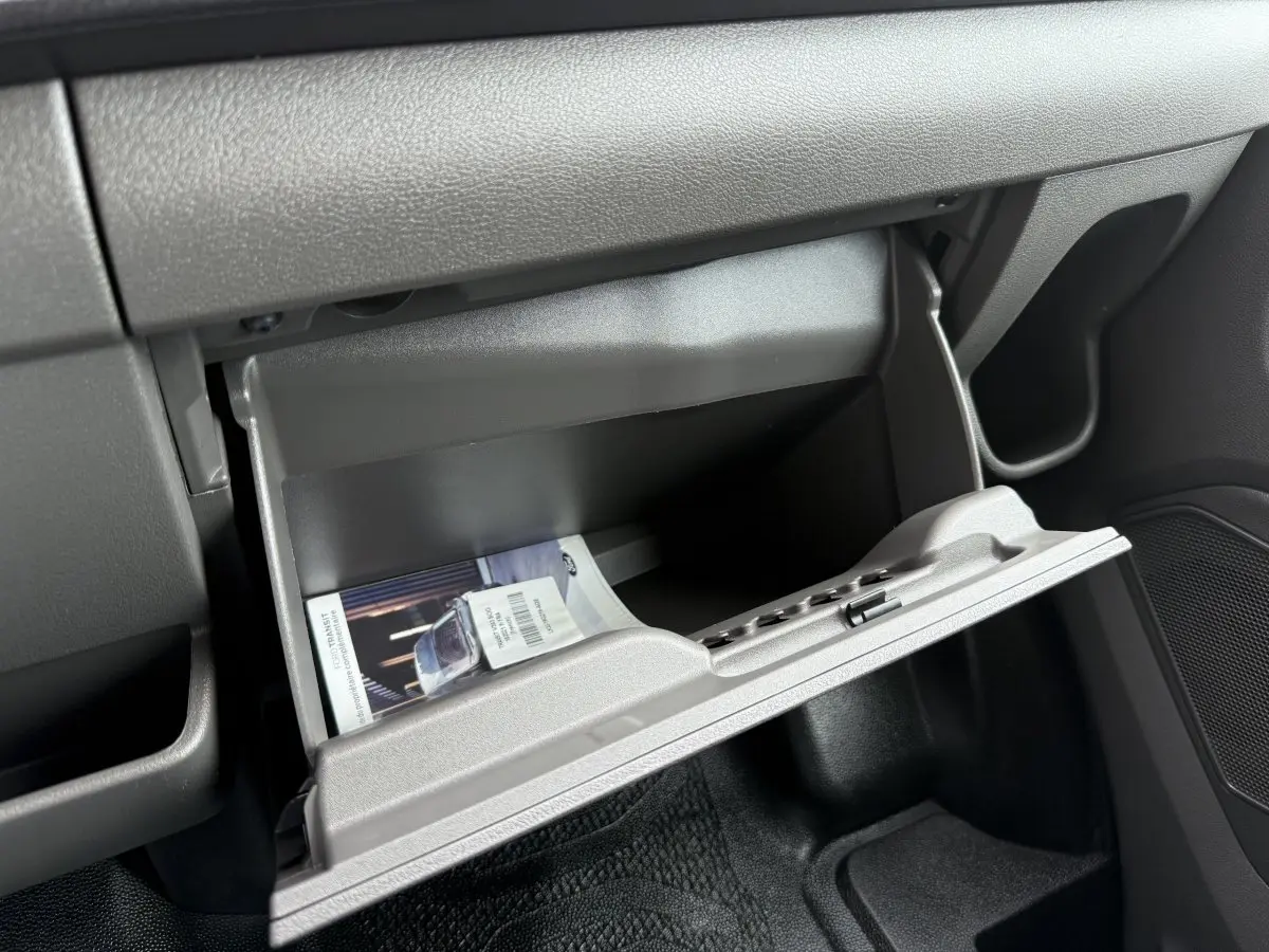 Vue intérieure du tableau de bord du Ford Transit Fourgon 2024, boîte à gants ouverte avec notice visible.