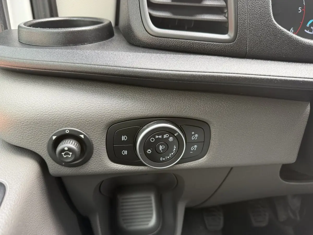 Gros plan sur le panneau de commande des phares et réglage du tableau de bord du Ford Transit Fourgon blanc 2024.