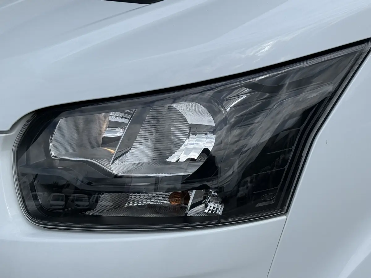 Gros plan sur le phare avant droit du Ford Transit Fourgon blanc 2024, mettant en valeur son design moderne.