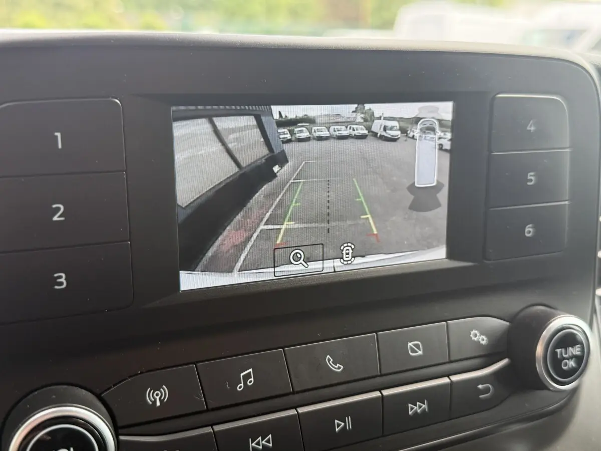 Écran de caméra de recul du Ford Transit Fourgon blanc, vue arrière avec lignes de guidage colorées.