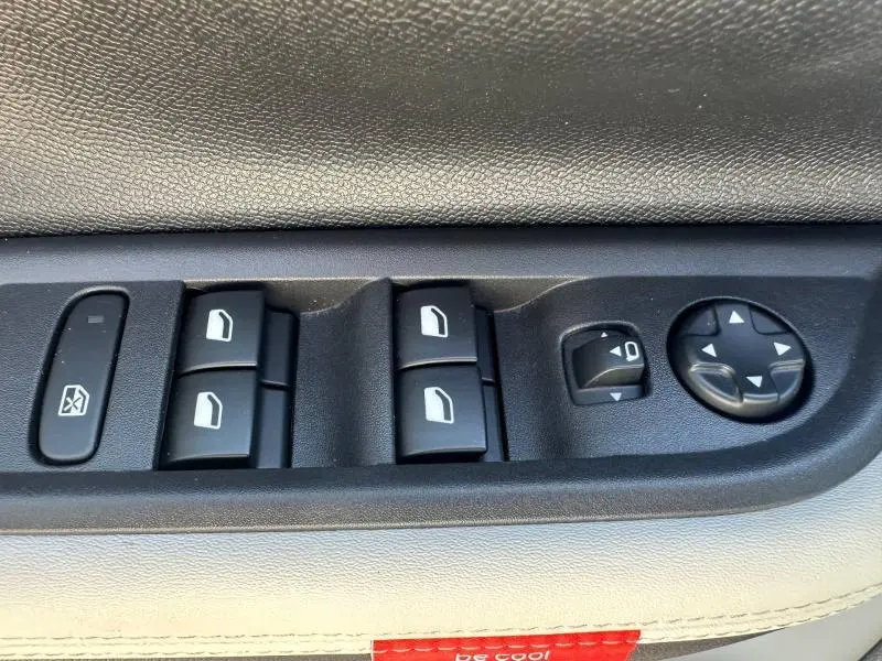 Gros plan sur les commandes de lève-vitres et réglage des rétroviseurs côté conducteur de la Citroën C3 Bright Blue avec toit noir.