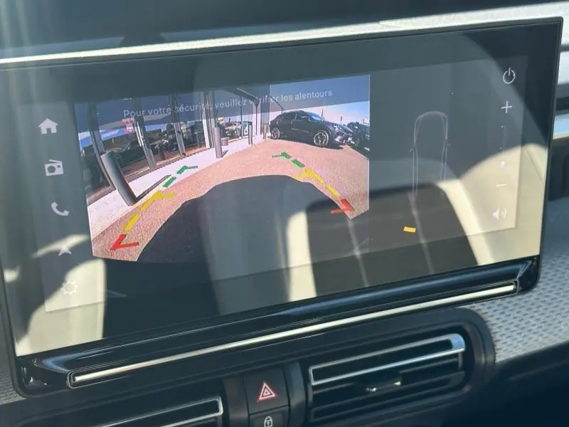 Écran tactile intérieur montrant la caméra de recul avec vue arrière sur un véhicule noir stationné.