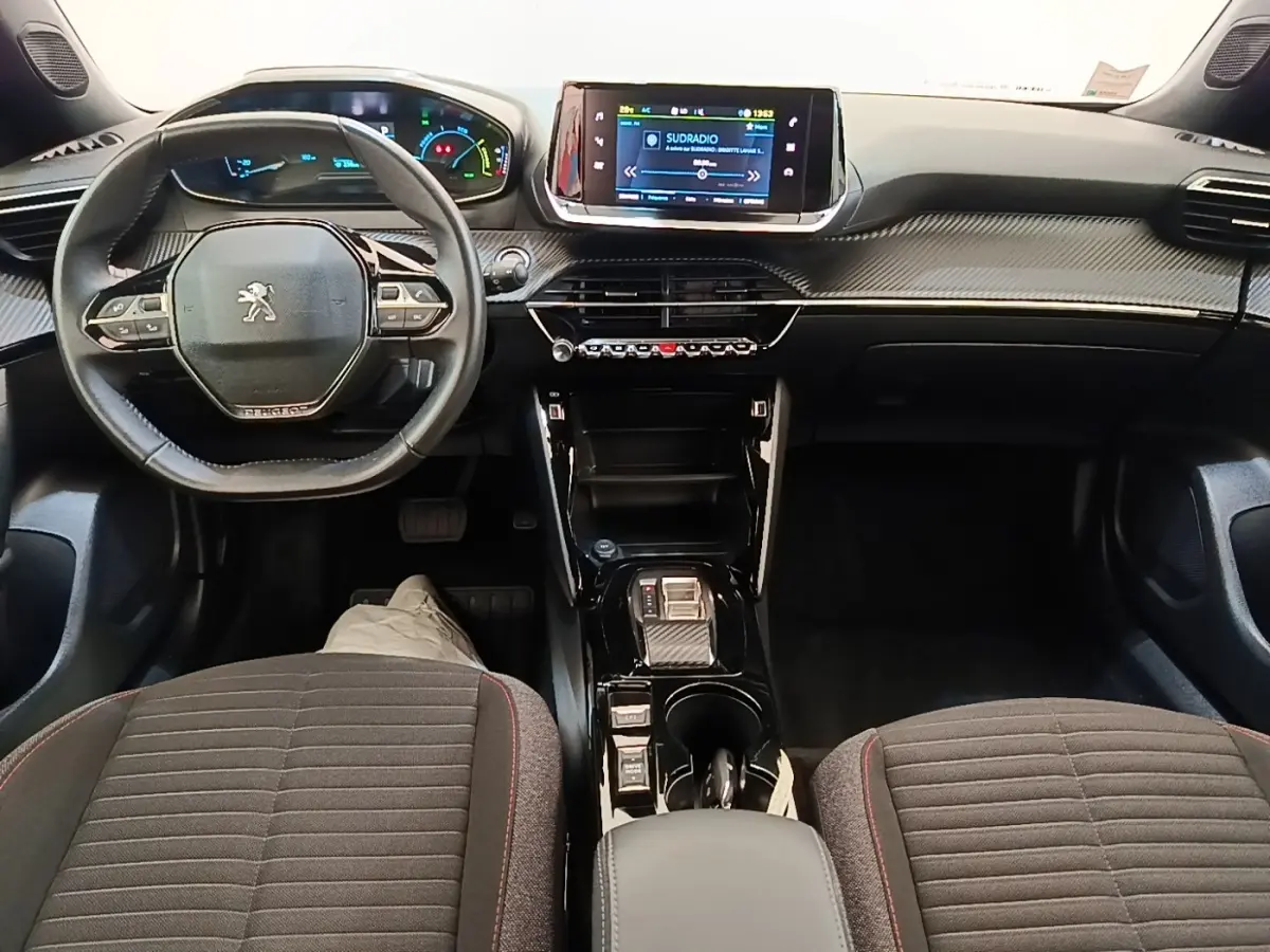 Vue intérieure avant du Peugeot E-2008 électrique, tableau de bord moderne avec écran tactile central et volant multifonctions.