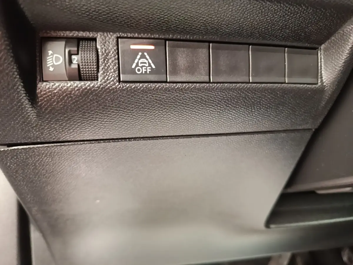 Gros plan sur les commandes noires du tableau de bord côté gauche du Peugeot E-2008 électrique gris clair 2023.