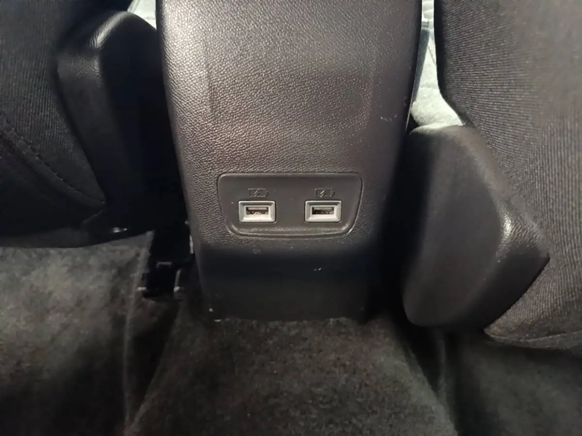 Gros plan sur les ports USB doubles arrière intégrés dans la console centrale noire du Peugeot E-2008 électrique gris clair.