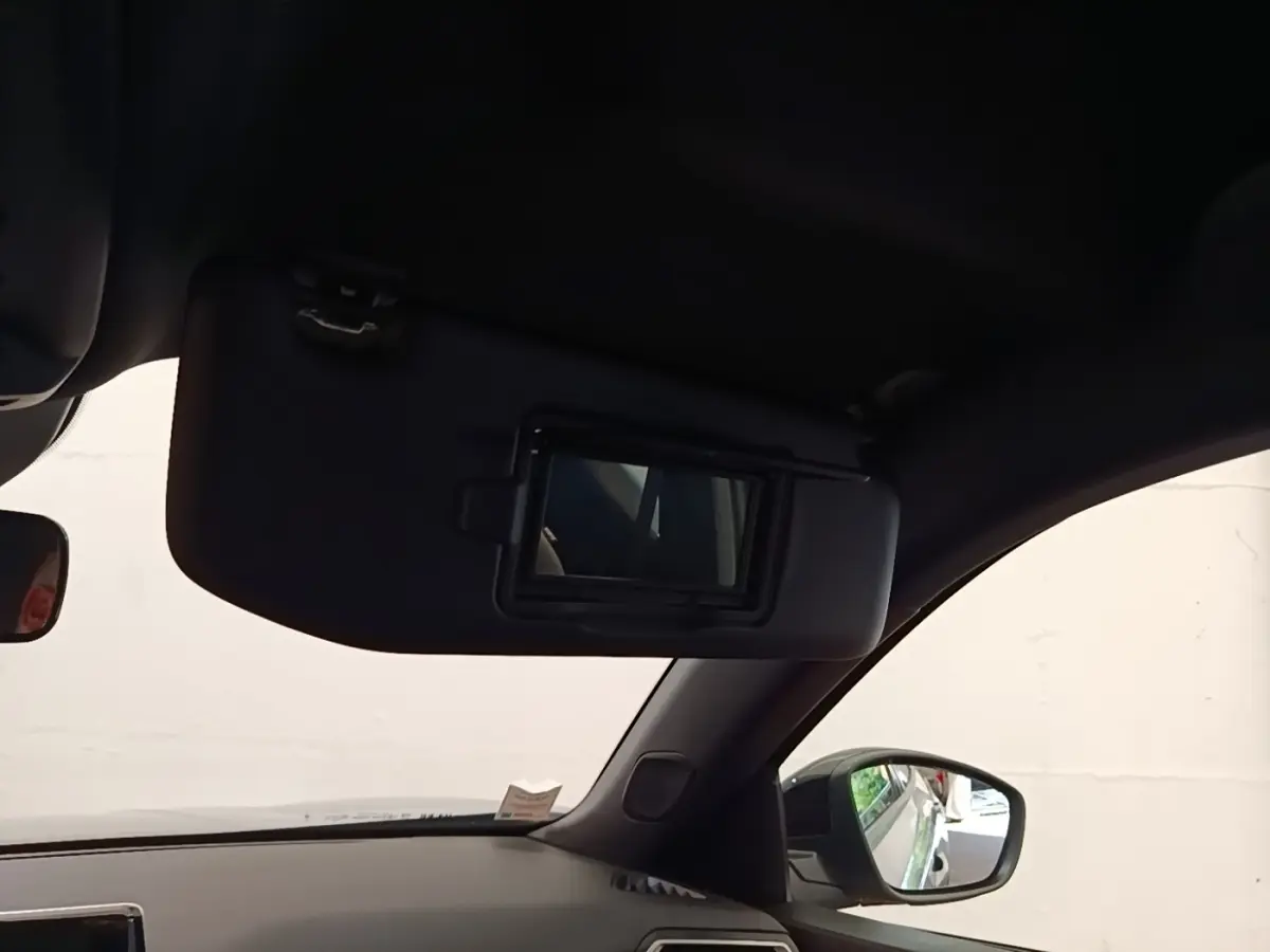 Intérieur côté conducteur du Peugeot E-2008 gris clair 2023, avec pare-soleil et miroir de courtoisie ouvert.