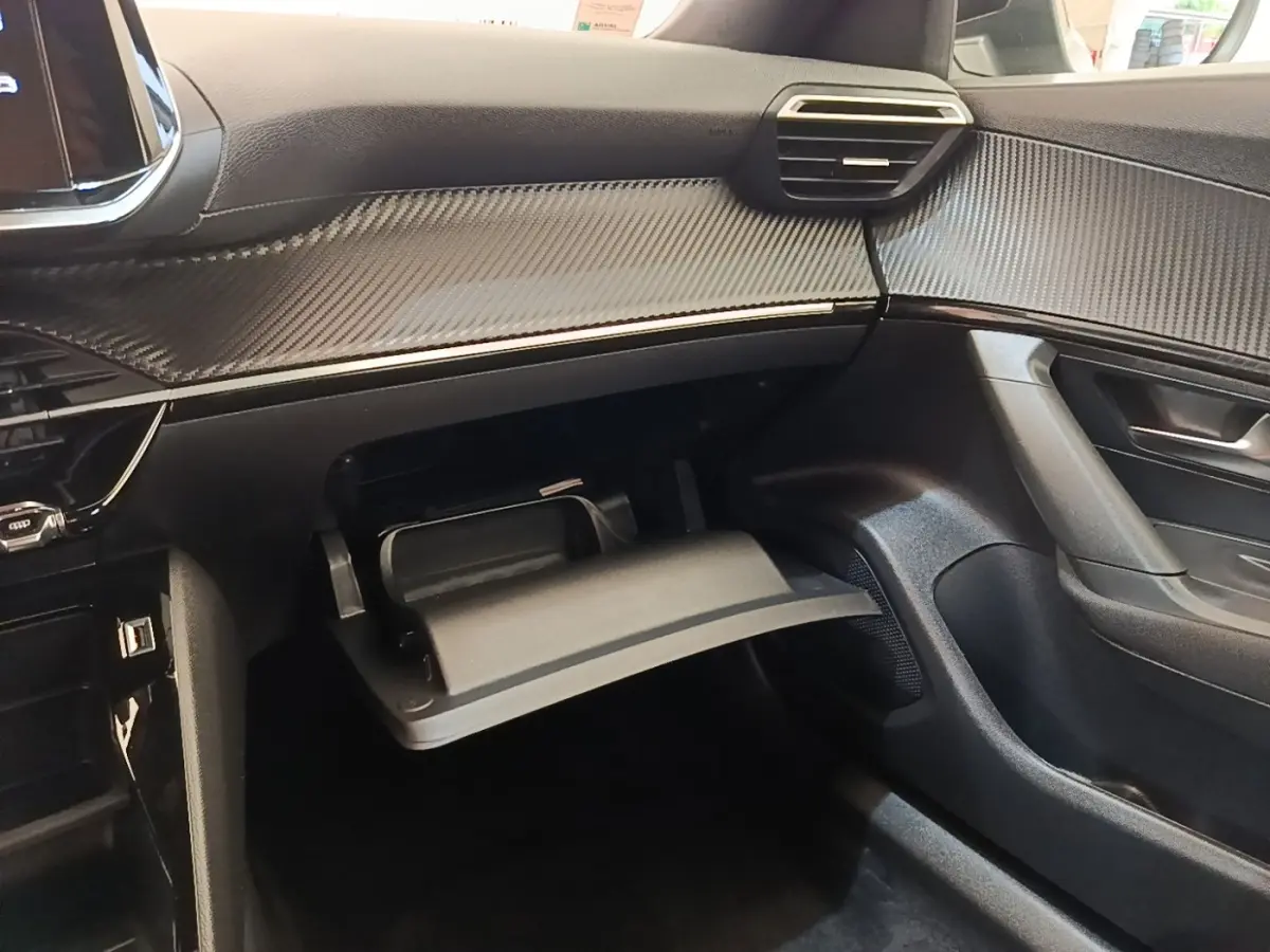 Intérieur côté passager du Peugeot E-2008 gris clair 2023, avec boîte à gants ouverte et tableau de bord texturé.