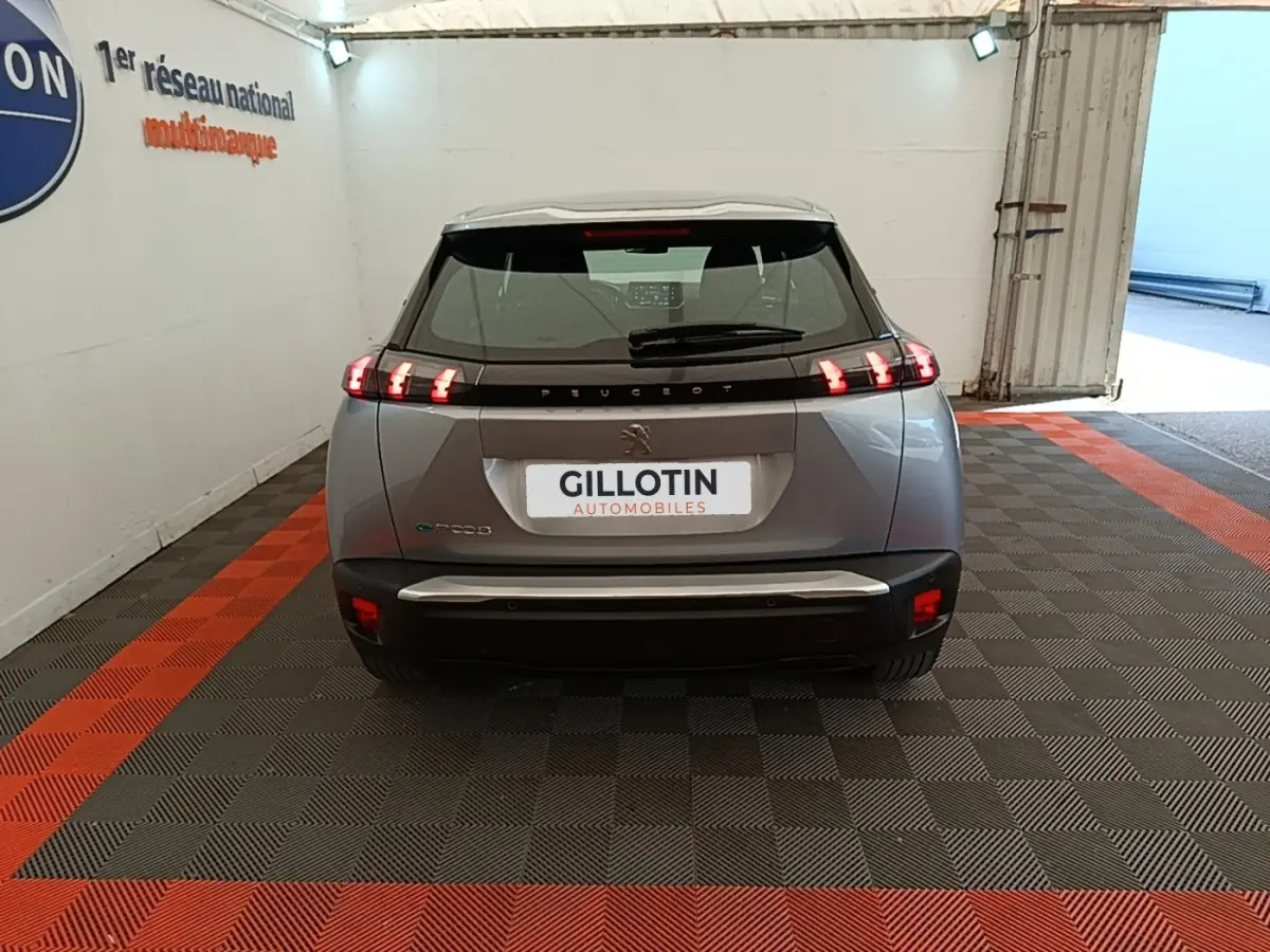Vue arrière du Peugeot E-2008 électrique gris clair 2023 avec feux LED caractéristiques et toit noir contrasté.