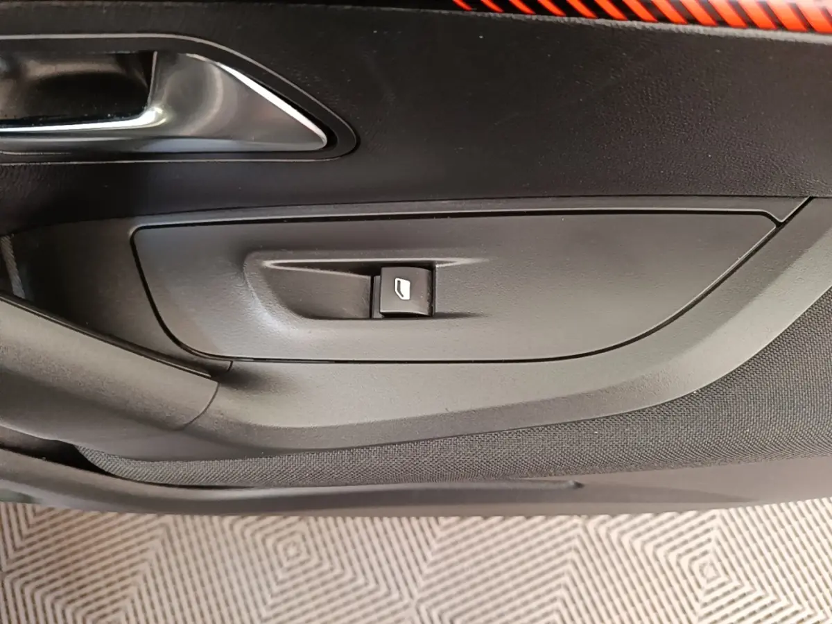 Détail de la commande de lève-vitre côté gauche intérieur d'une Peugeot E-2008 électrique gris clair.