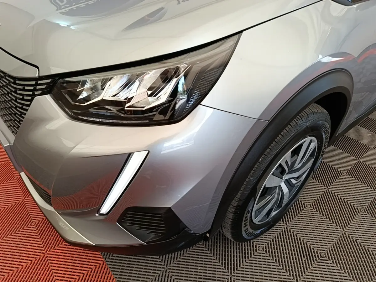 Gros plan sur l’avant droit gris clair du Peugeot E-2008 électrique avec phares LED et jante alu distinctive.