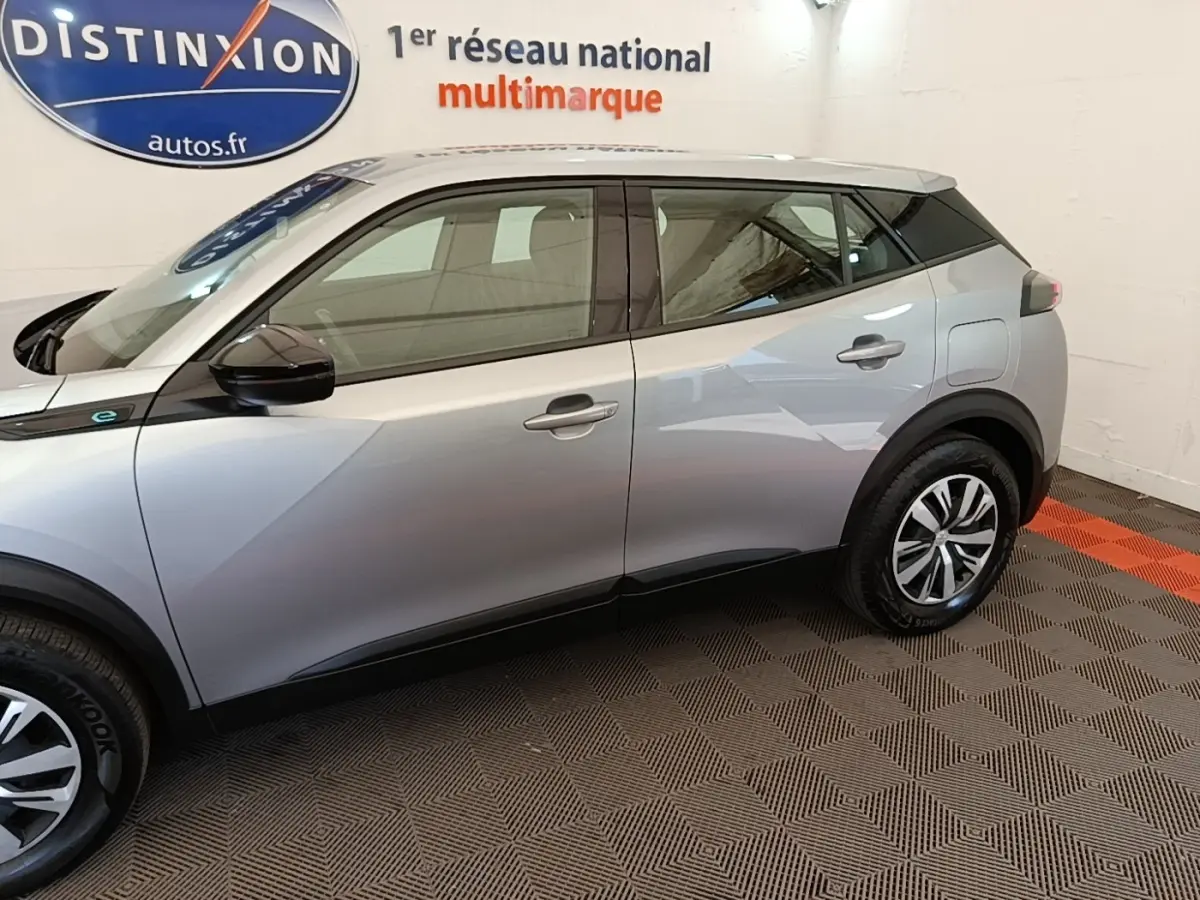 Profil côté gauche du Peugeot E-2008 électrique gris clair 2023 avec jantes et rétroviseurs noirs.