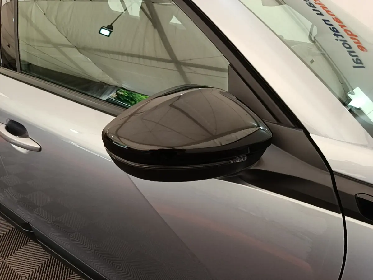 Vue rapprochée du rétroviseur droit noir sur la porte gris clair d’un Peugeot E-2008 électrique 2023.