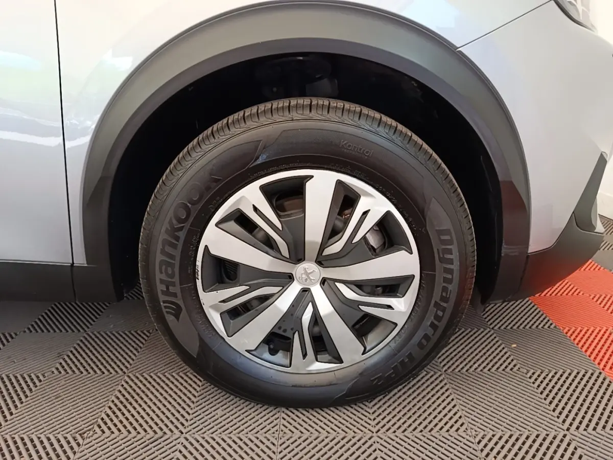Gros plan sur la roue avant gauche gris clair du Peugeot E-2008 électrique avec jante alliage et logo Peugeot central.