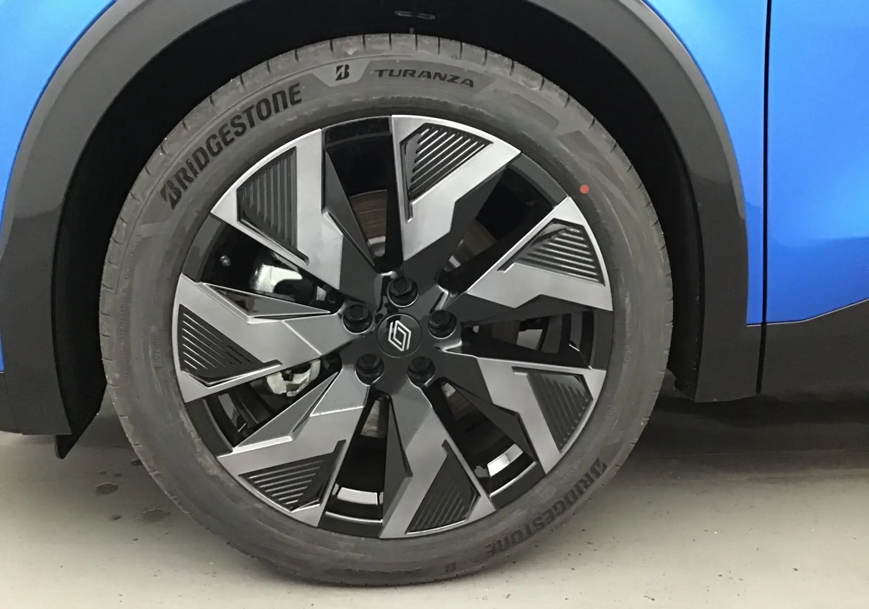 Gros plan sur la roue avant gauche du Renault Rafale Bleu Sommet avec jante alliage au design géométrique noir et argent.