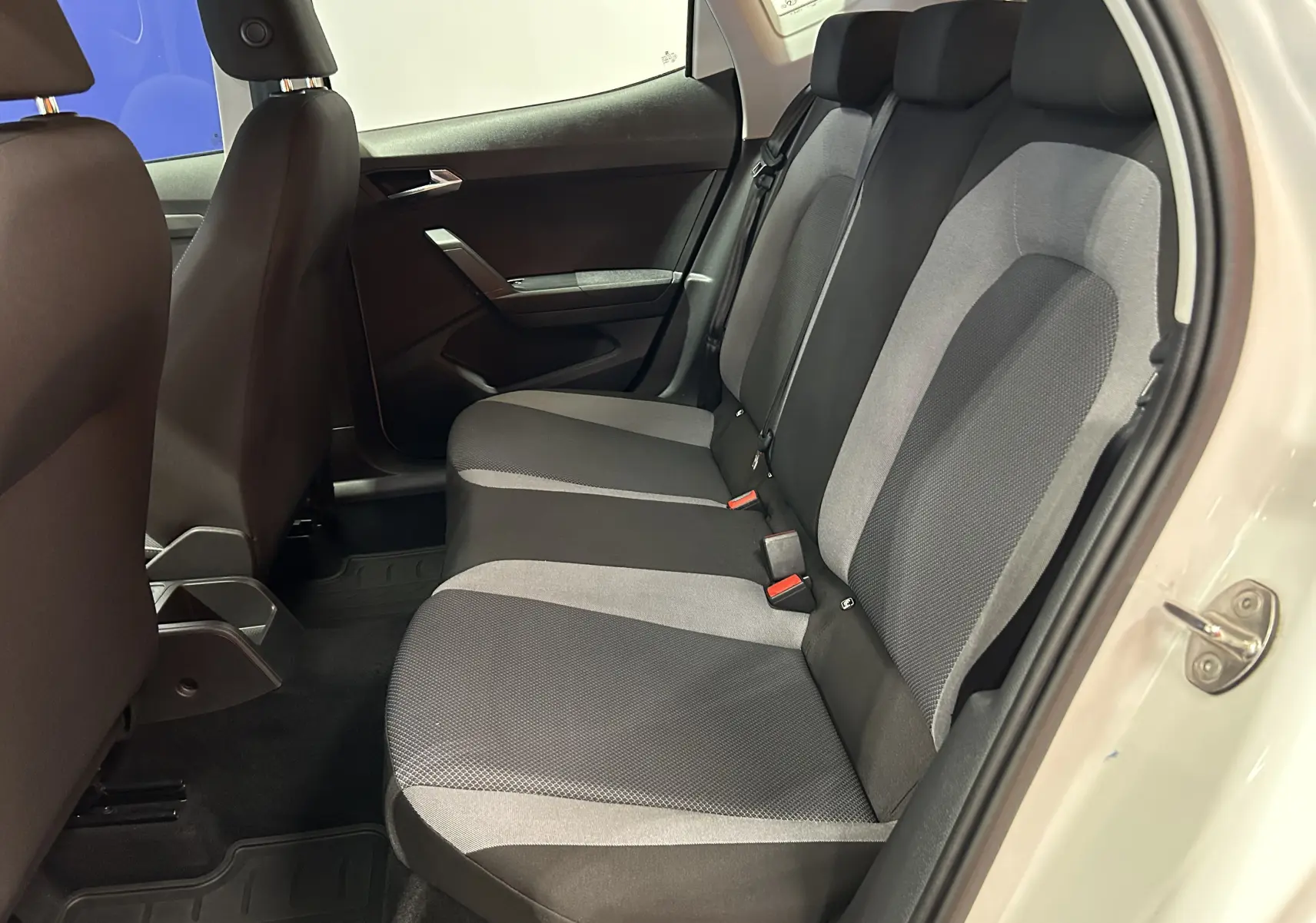 Vue intérieure côté droit des sièges arrière en tissu gris et noir d'une SEAT Ibiza blanche de 2019 avec portes ouvertes.