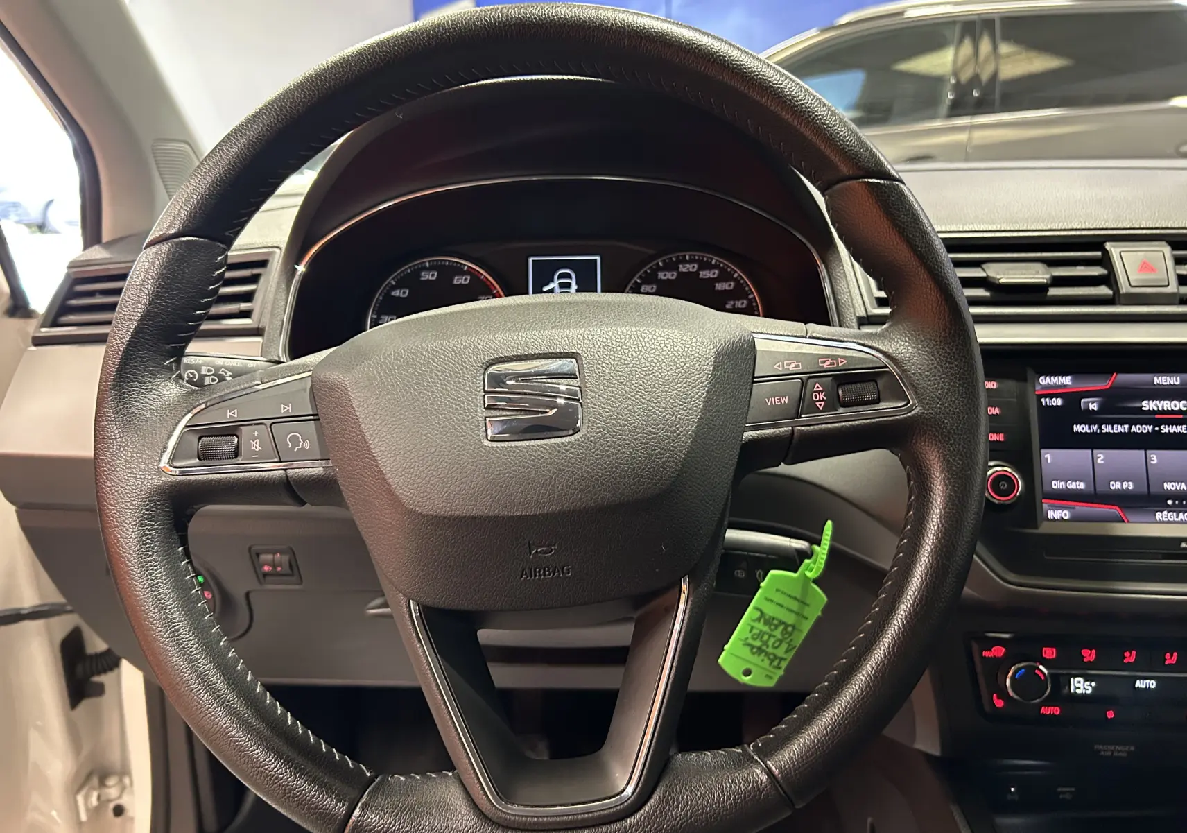 Vue rapprochée du volant en cuir noir d'une SEAT Ibiza 2019 avec tableau de bord et écran multimédia allumés.