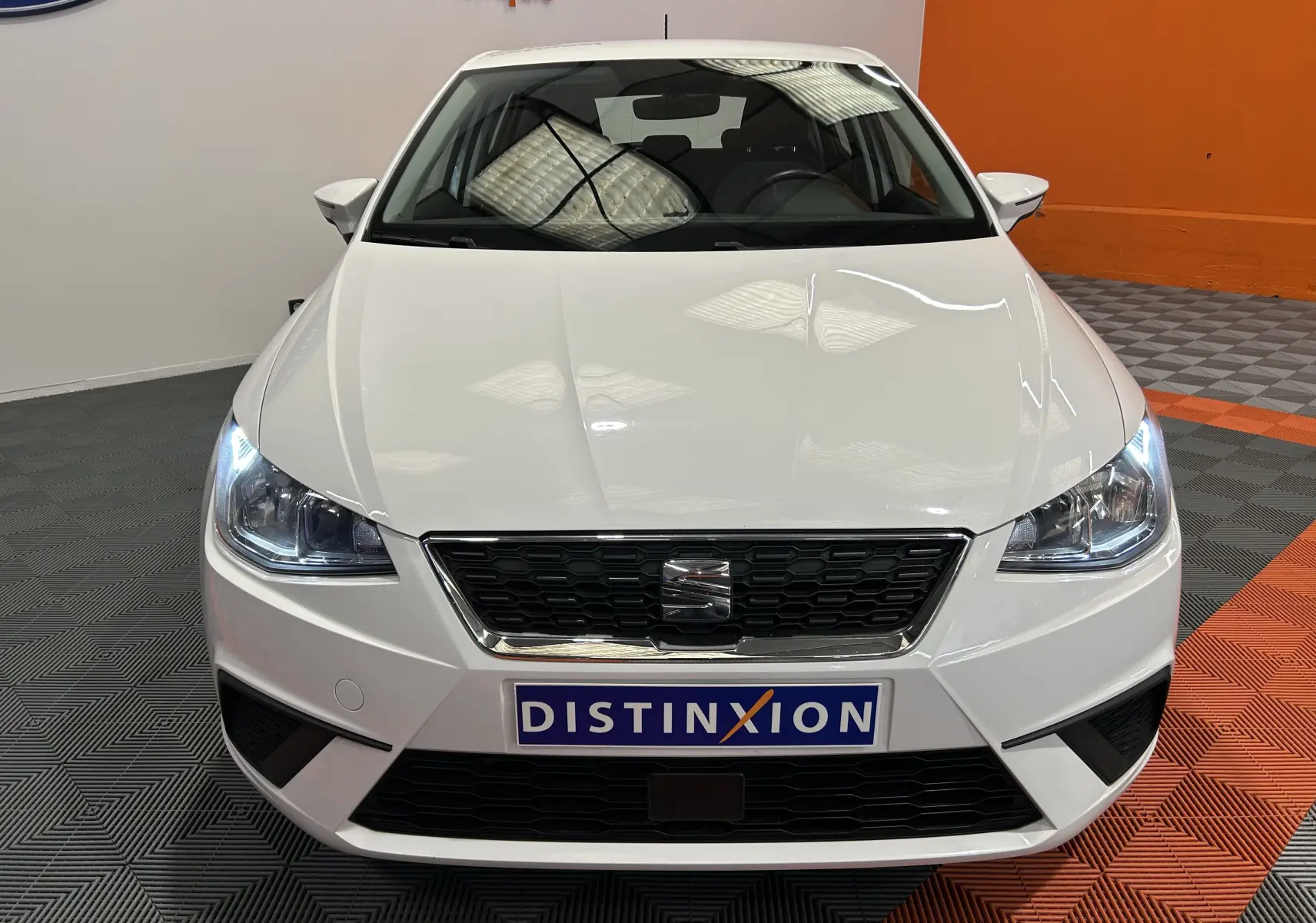 Vue frontale d'une SEAT Ibiza blanche de 2019 avec phares allumés et calandre noire distinctive.