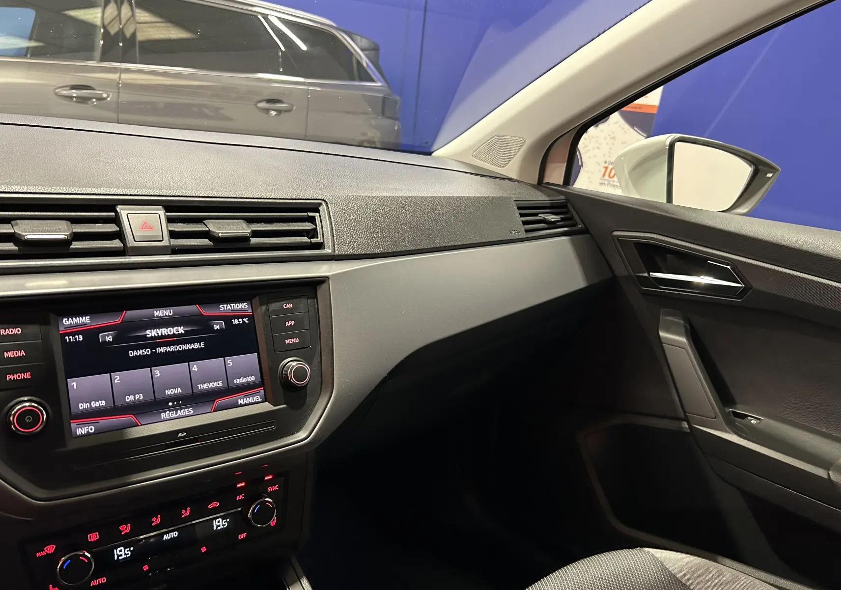 Intérieur côté passager de la SEAT Ibiza blanche 2019, tableau de bord et console centrale avec écran tactile allumé.
